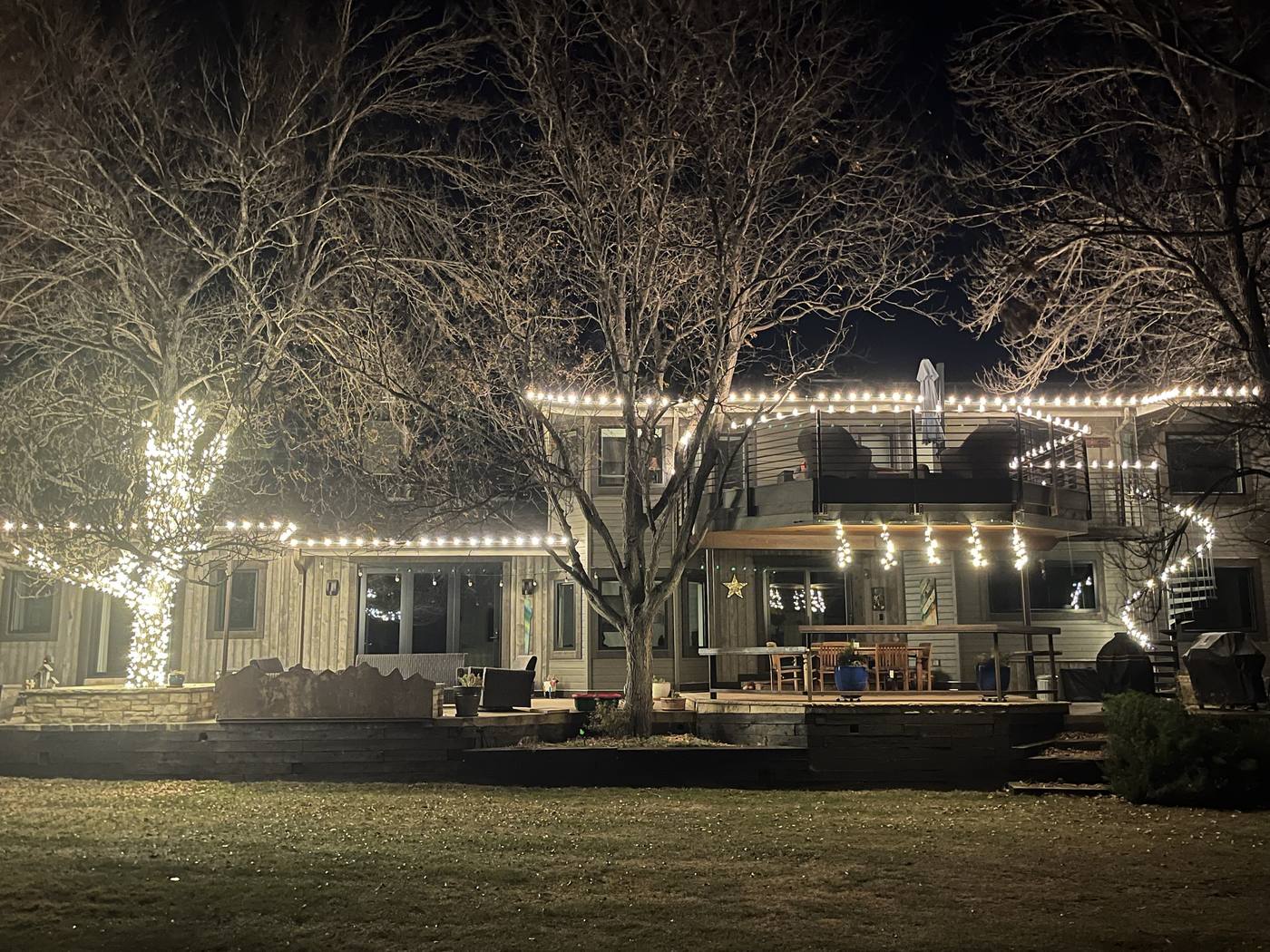 Backyard Christmas lights: wrapped tree, deck railing, and roofline in Boulder County, CO