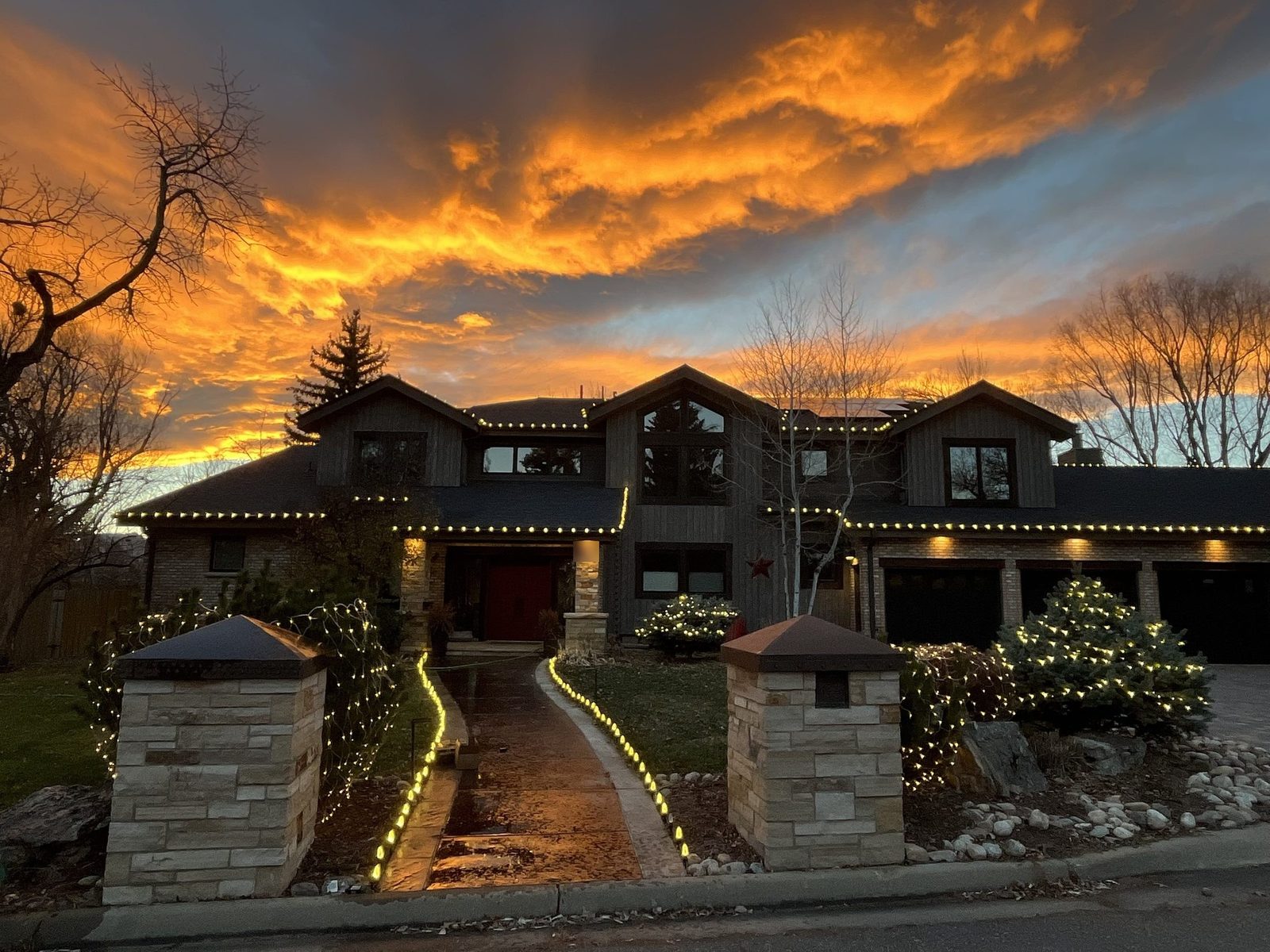 Christmas light installation on a Boulder County home at sunset